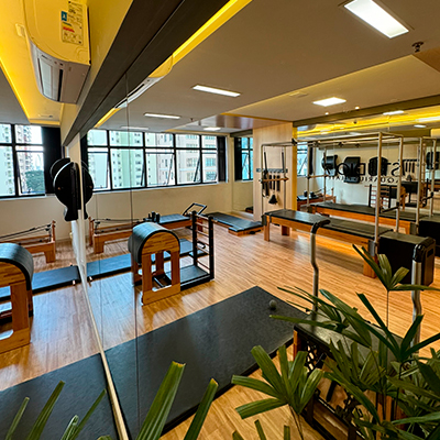 Vista ampla da Sala 58 da unidade Aquarius com equipamentos de pilates e janelas amplas com luz natural.